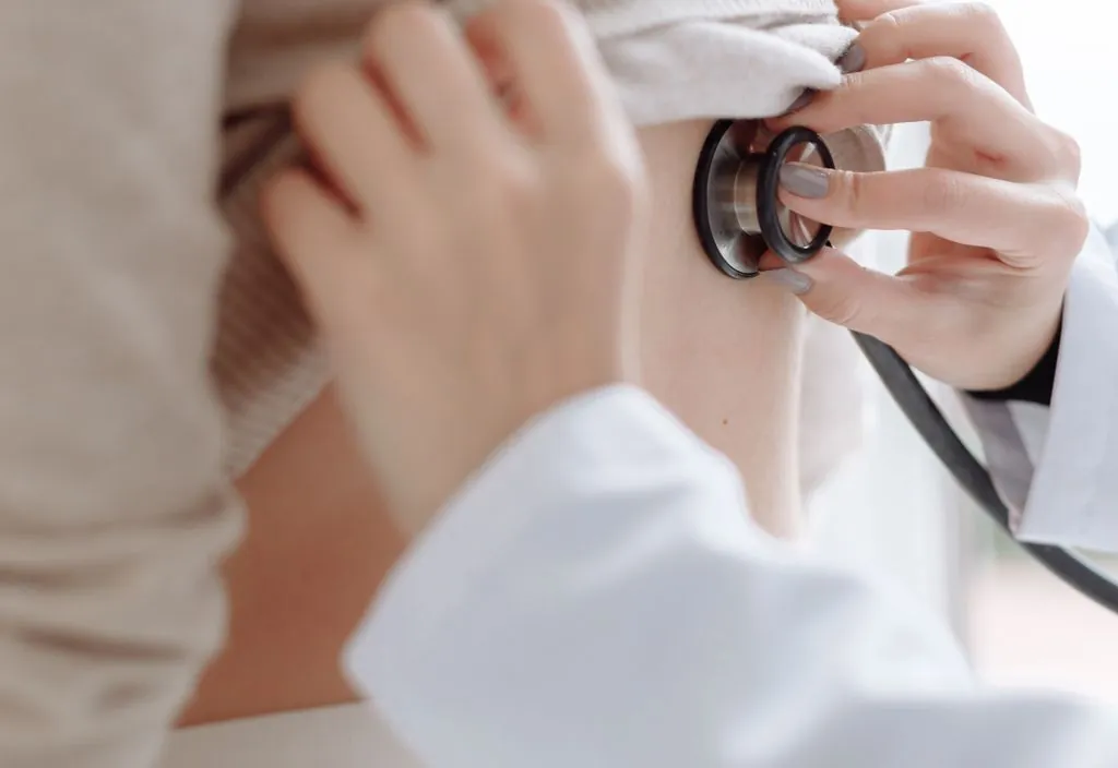 Médico examinando o abdômen do paciente com estetoscópio