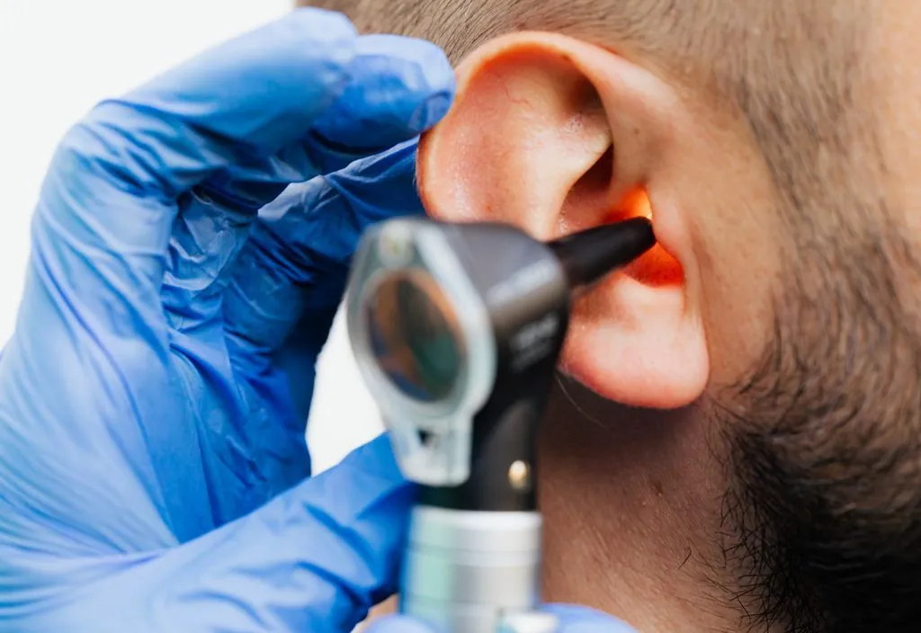 Otorrinolaringologista examinando o ouvido com otoscópio